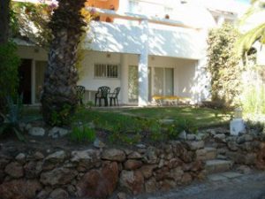 white Exterior of aparment building, with rock form garden