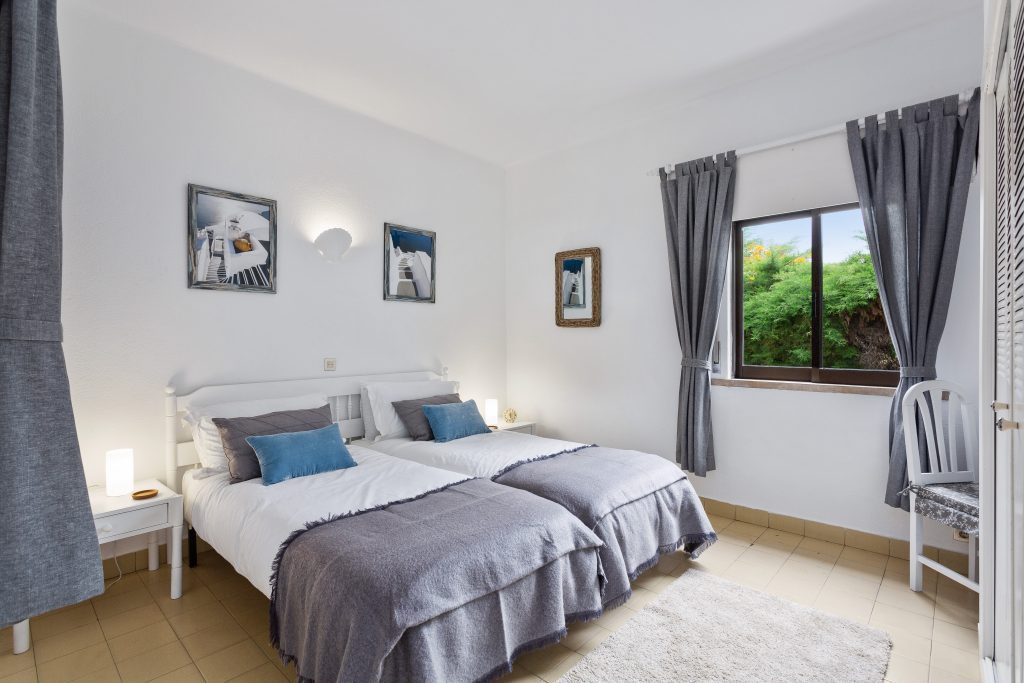 Apartamentos ferias Algarve, quarto com 2 camas e uma janela decorado em cinza e branco