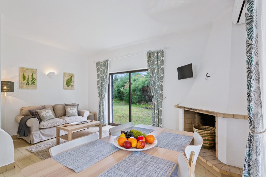 apartamentos de ferias vilamoura com sala Mesa com cadeira, nima sala com lareira e sofa.