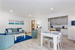 Elegant open plan lounge & dining area with Kitchen in the background all in shades of blue.