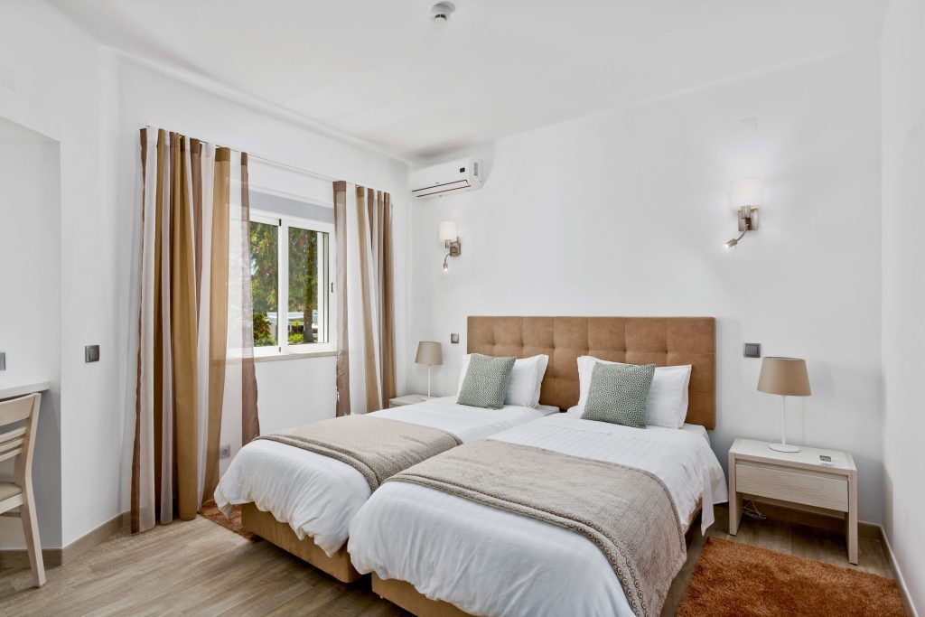 Prado Villas - bedroom with two beds in brown and white colours