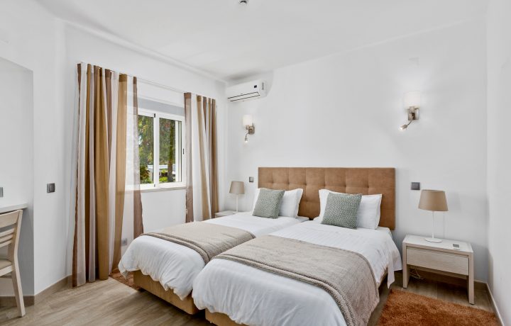 Prado Villas - bedroom with two beds in brown and white colours