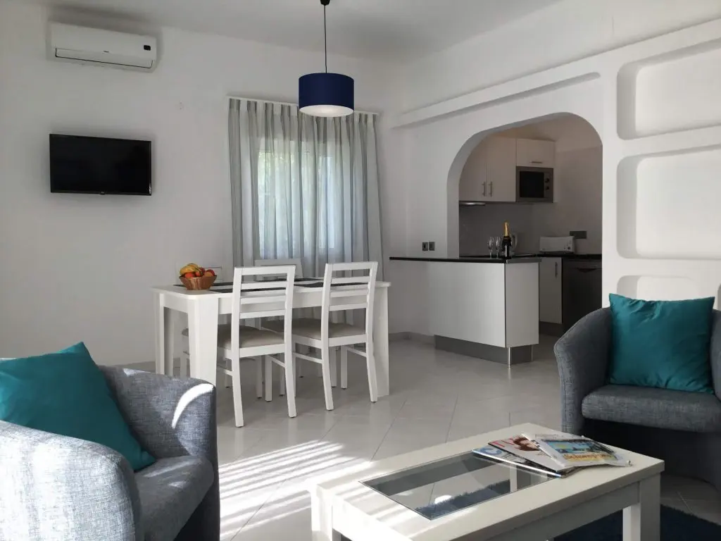 apartamentos férias Vilamoura com mesa e cadeiras brancas e sofa cinzento