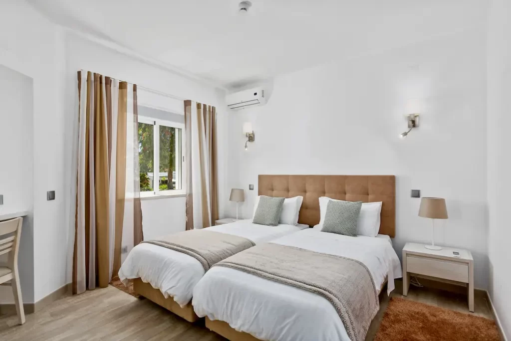 Bedroom with two beds. white covers with brown and cream curtains
