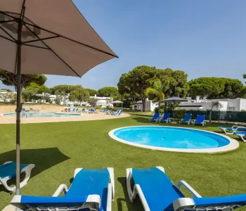 Childrens pool area with blue sunbeds and green grass