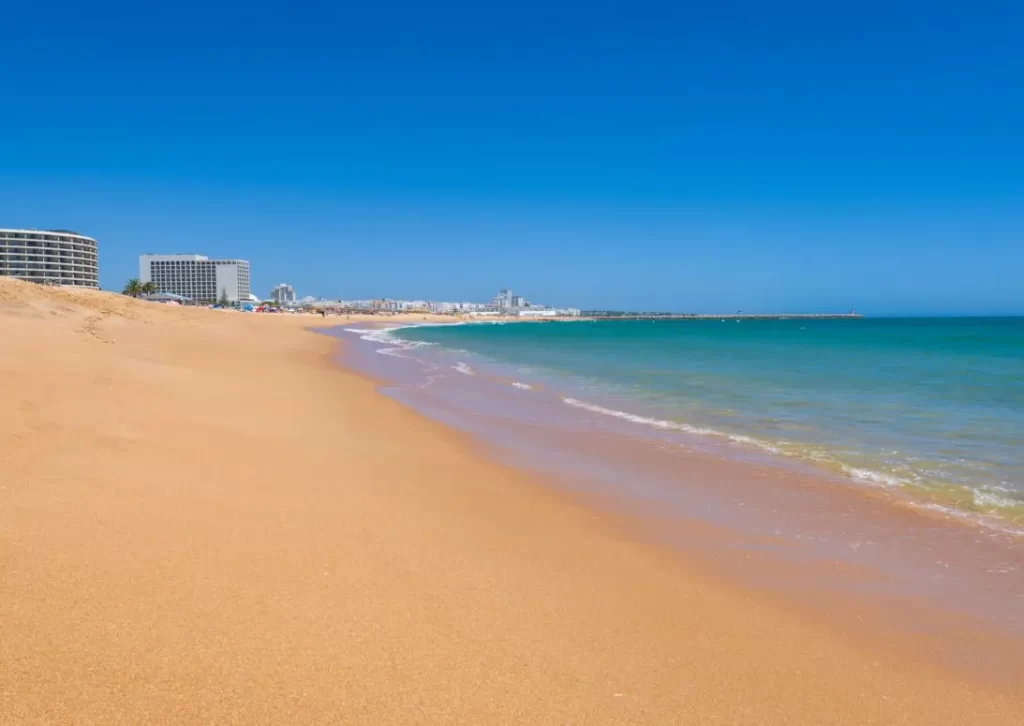 Vilamoura-family-holidays-vilamoura-beach long golden sand beach with blue skies and blue ocean water at Vilamoura beach